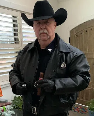 Older gentleman wearing a cowboy hat black leather jacket about the light a cigar