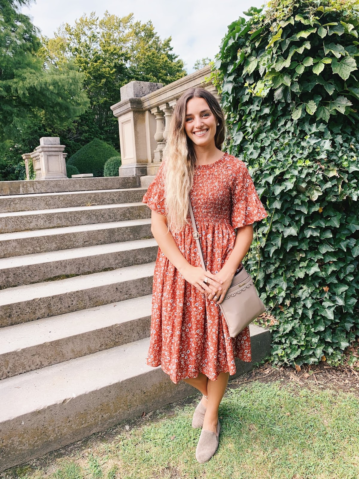 Girl in a floral dress posing by a grand staircase