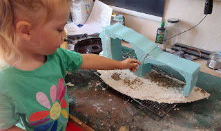 Rosie sprinkles gravel on the terrain piece