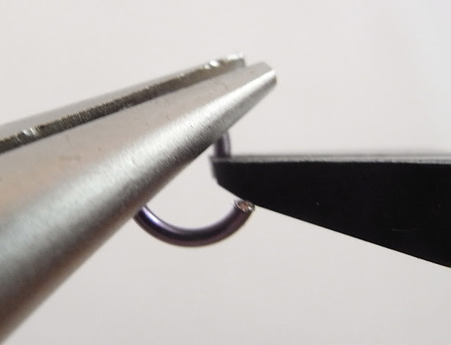 Using flush cutters to trim the jagged end of the jump ring so that it is flat