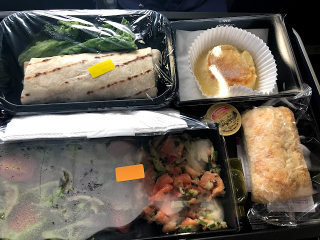 A sectioned box containing salads, a chicken wrap, a roll , and dessert