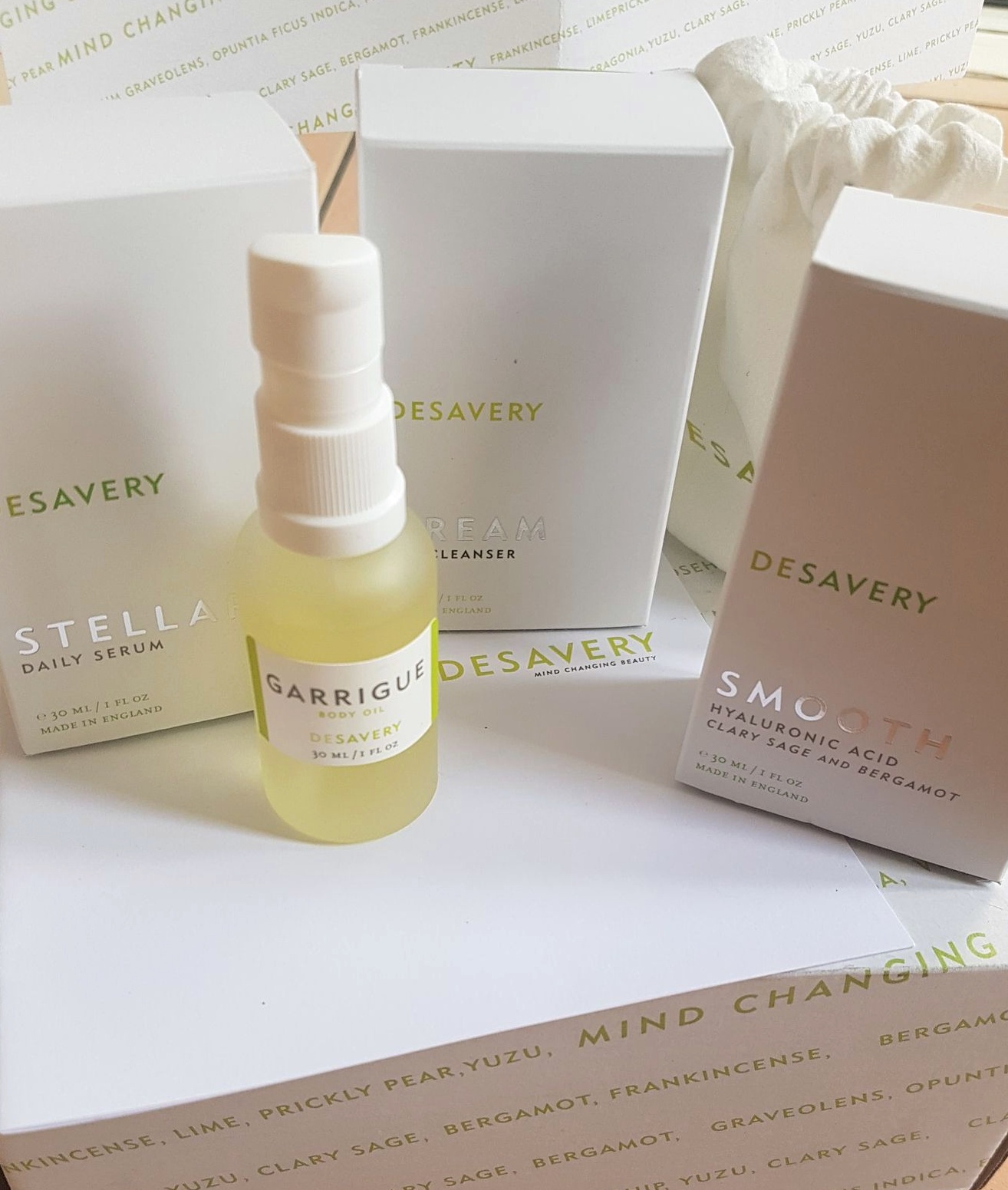 a selection of Desavery Skincare products including Stellar Daily Serum, Garrigue Body Oil, Dream Oil Cleanser, and Smooth Hyaluronic Acid all on a white box