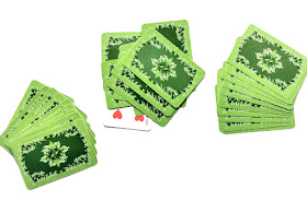 na zdjęciu stos kart odrzuconych na środku stołu a po bokach leża karty graczy ułożone w zakryte wachlarze