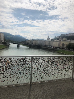 Desde un puente lleno de candados. Se ve el rio, sus puentes, a los lados los monumentos, al fondo las montañas.