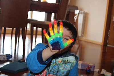 Criança com as mãos pintadas com tinta para fazer um arco-íris