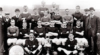 MANCHESTER UNITED F. C. - Manchester, Inglaterra - Temporada 1908-09 - Alex Downie, Burgess; Taylor (director) , J. Nuttall (asistente entrenador), Harry Stafford (director), H. Broomfield, G. Stacey, D. Duckworth, R. Holden, Alex Bell, H. Moger, Fred Bacon (entrenador), J. E. Mangnall (sec. managers); J. Picken, J. Bannister, J. Turnbull, Charlie Roberts, Halse y Sandy Turnbull; Billy Meredith y George Wall - La plantilla del Manchester posa con los tres trofeos ganados: FA Charity Shield Cup, Championship Cup y Manchester Cup