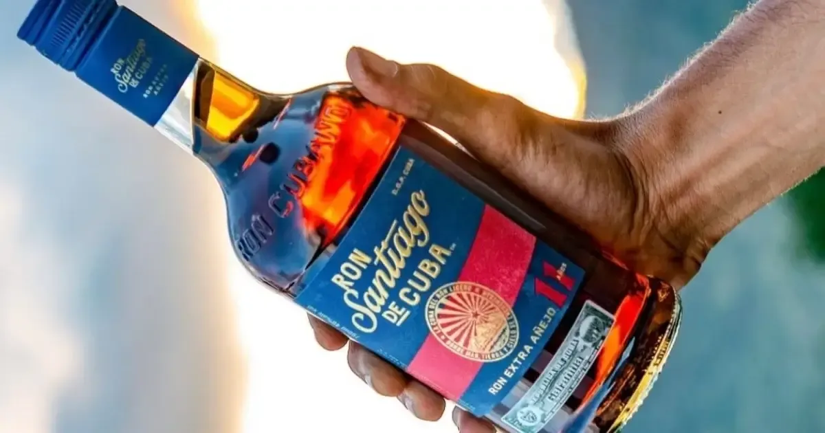 Botellas de ron cubano en una destilería con barriles de roble, reflejando la crisis azucarera.