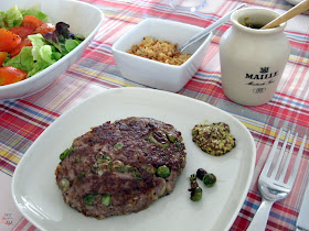 Hamburguesa de ternera aderezada con guisantes, habitas tiernas y cebolla frita.