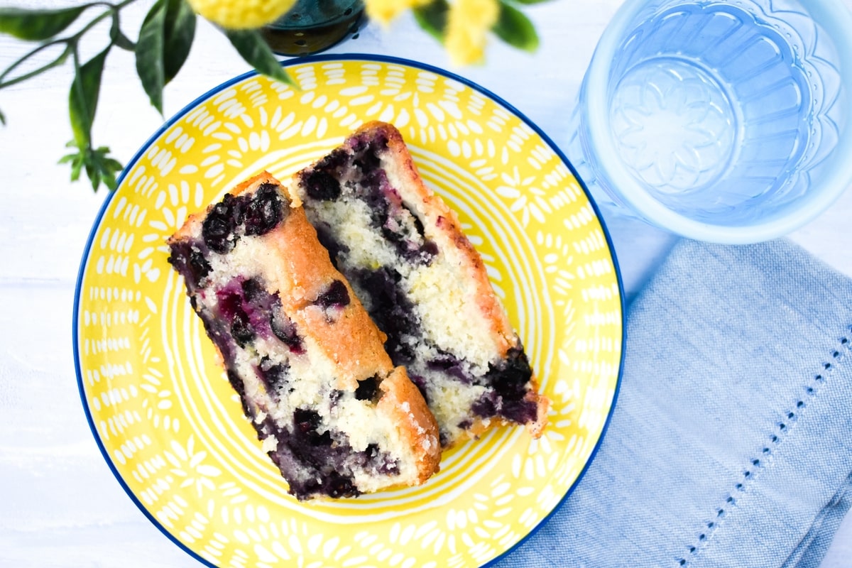 Slices of vegan blueberry lemon loaf cake on a yellow teaplate