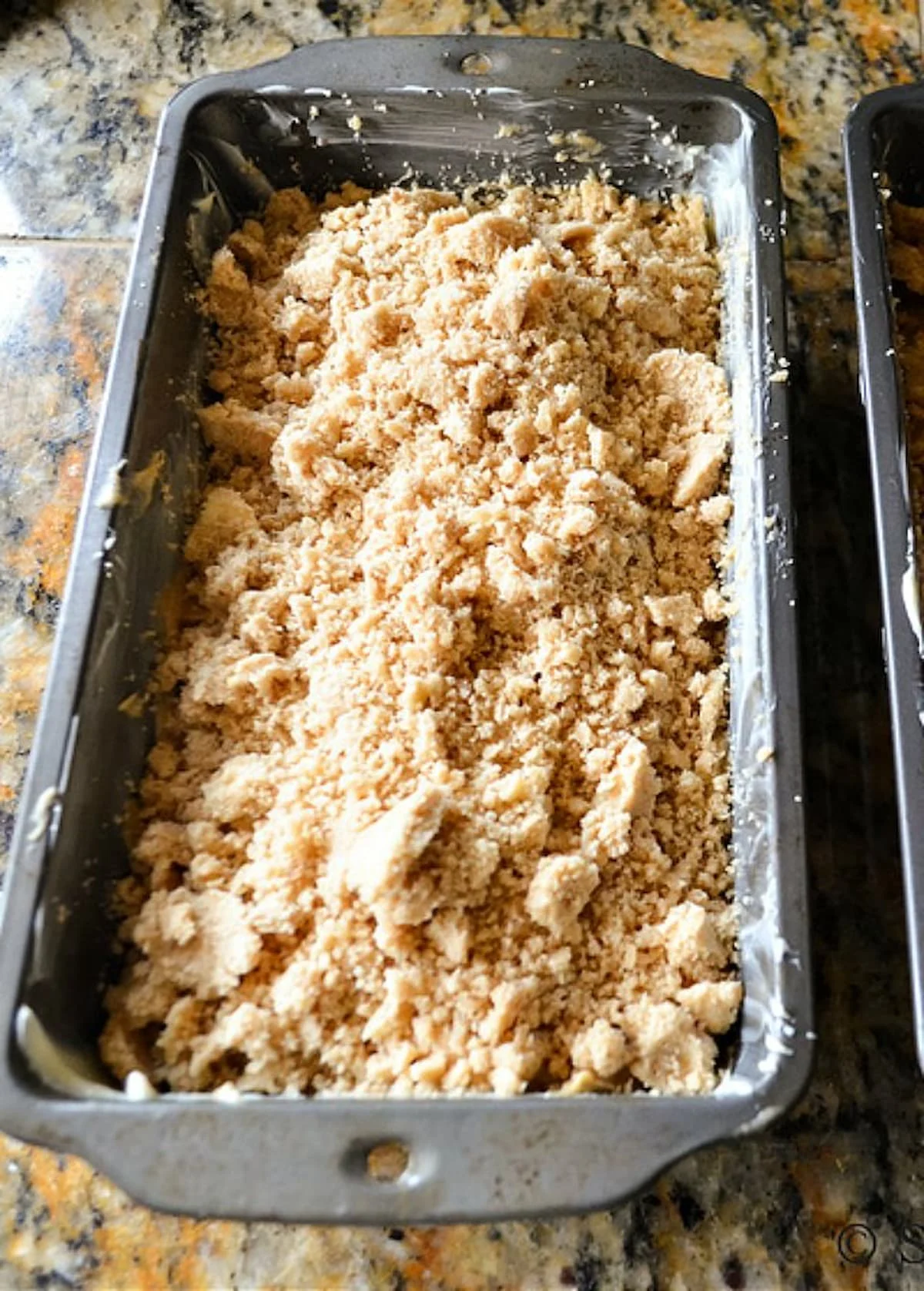 Zucchini Bread batter in a loaf pan topped with brown sugar crumb.
