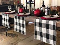 A table set with black and white plaid clothes and red ornaments and plates