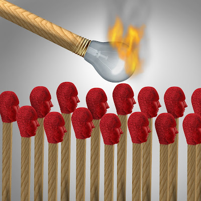 Figurative illustration of burning light bulb match about to set light to lots of matches with red human-shaped tops