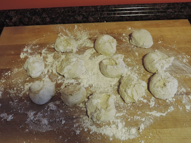 The dough for the homemade dinner rolls sectioned into 12 little balls on the floured cutting board.