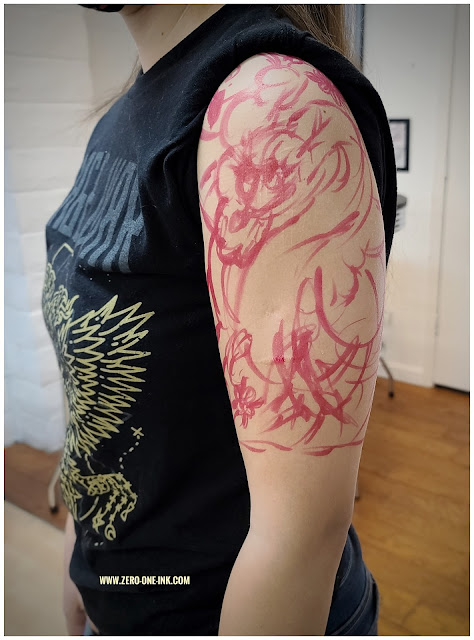 young woman standing on a with room showing a sketch of a Japanese dragon style tattoo