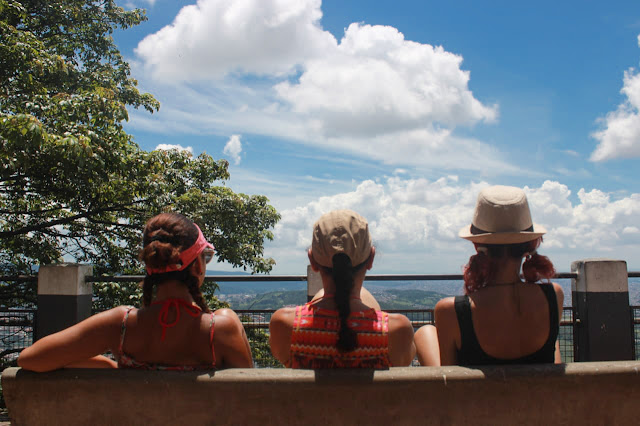 Imagem de três mulheres sentadas no banco olhando a cidade de são paulo de cima