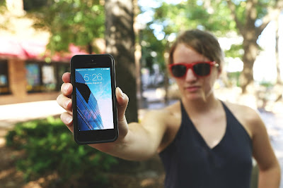 Girl wearing sunglasses shows the screen of her smart phone