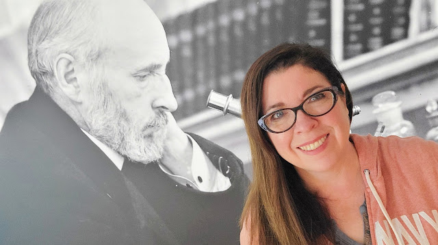 This is a portrait of artist Dawn Hunter standing in front of an oversized photograph of Cajal.