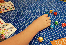 Playing Dice Academy by Blue Orange Family Games hand on table with several different dice