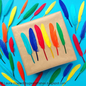 A brown paper parcel decorated with a rainbow of bright feathers