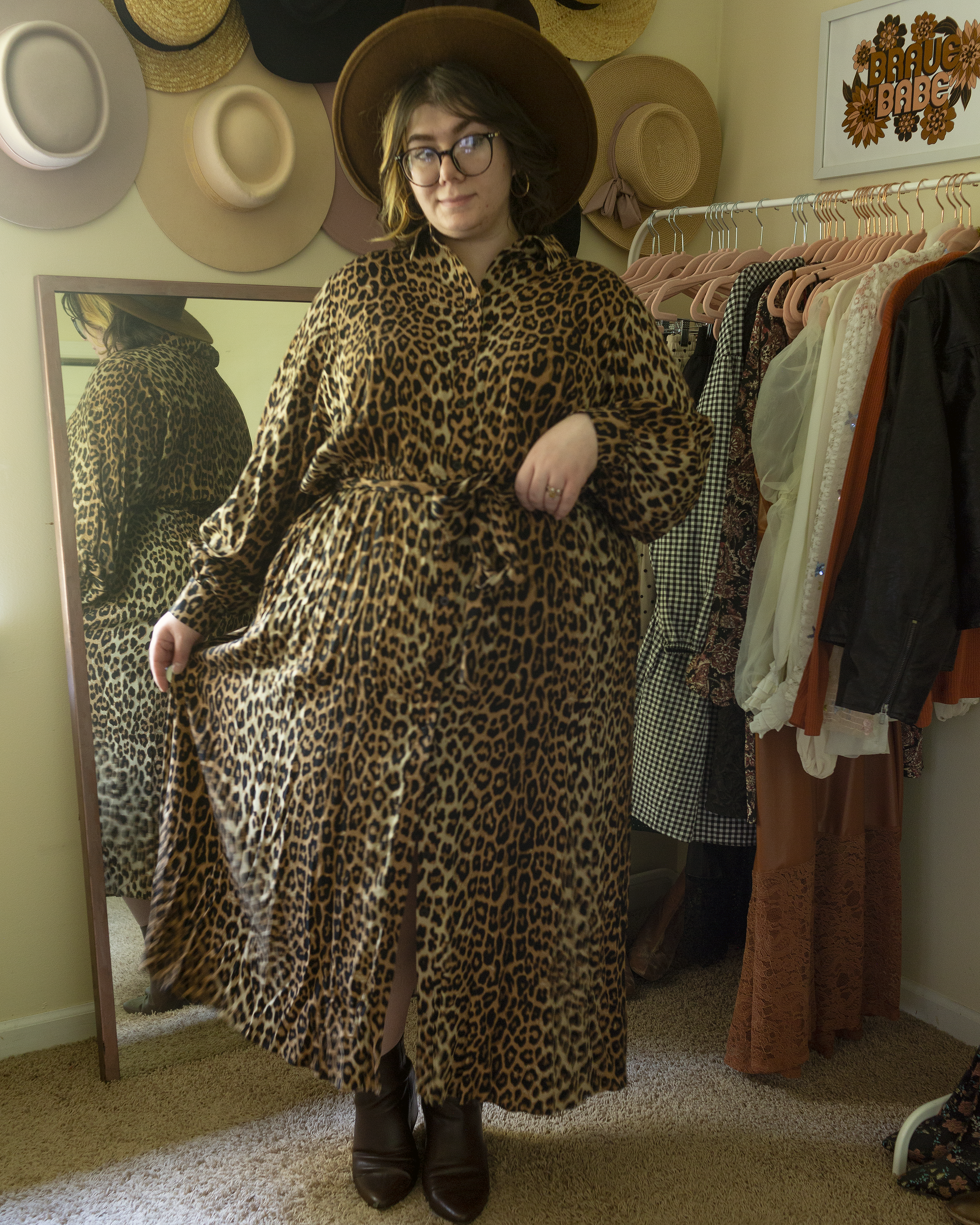 An outfit consisting of a black on brown leopard print button up collared shirt dress with walnut brown boots.