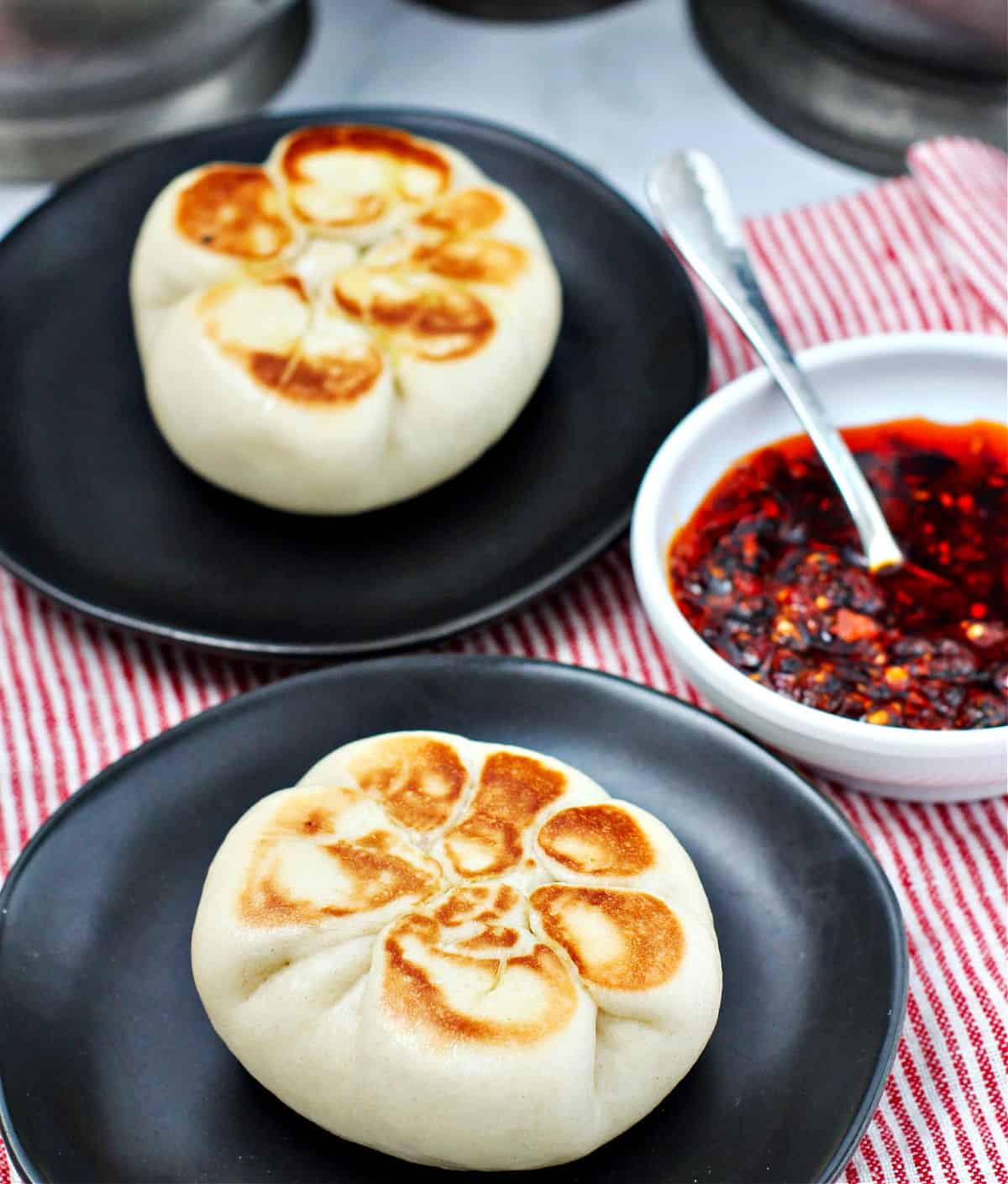 Steamed Chicken and Vegetable Buns on black plates.