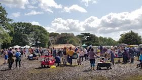 Village Green at Just So Festival 2019 Saturday afternoon 6 inch deep in thick mud but with lots of people watching trapeze artist