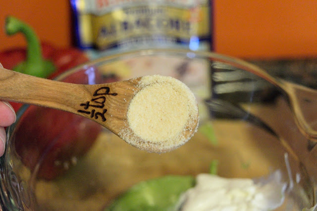 A picture of a measuring spoon, over the mixing bowl, with onion powder in it. 