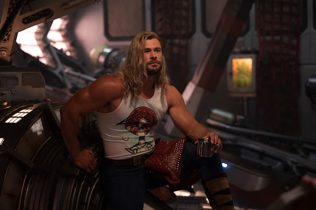 Thor sitting in a space seat looking very muscular