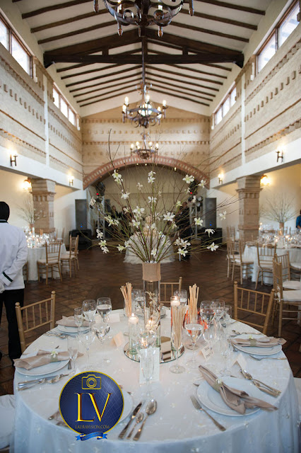 mesa elegante con arreglo floral alto para una boda, al fondo el ponque y la pista de baile