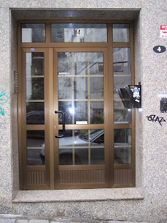 Portal de entrada anodizado  en color bronce.  Doble acristalamiento  con cuadricula interior