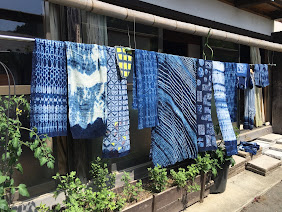 A variety of indigo cloth creations hanging outside to dry.