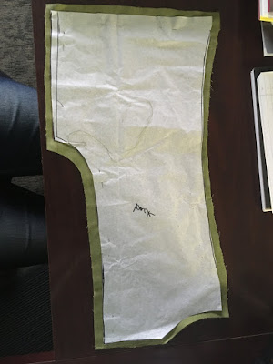 A tissue-paper vest back pattern, pinned to a piece of green linen cut slightly larger.