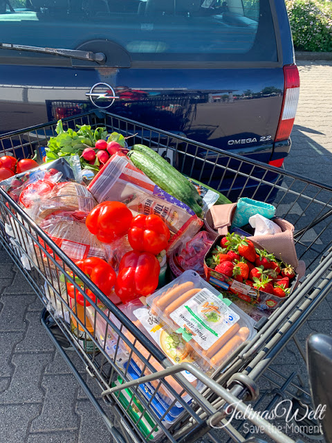 Voller Einkaufswagen vor dem Auto