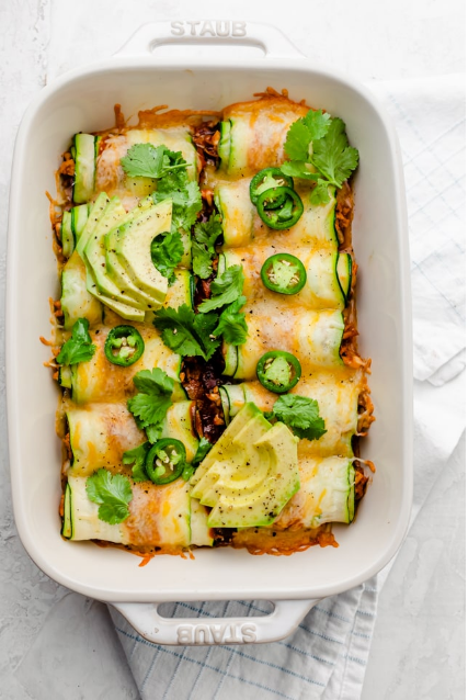 Zucchini Enchiladas - Swap the tortillas for thinly sliced zucchini, and try this low carb keto friendly Zucchini Enchiladas. They're made w/ shredded chicken and sure to impress!