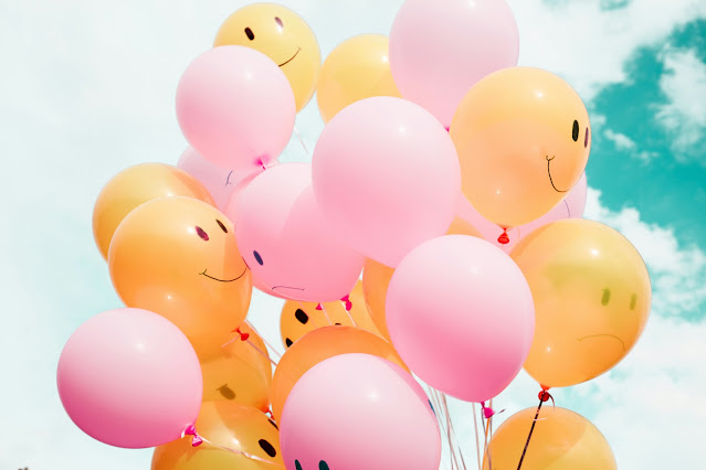 bunch of pink and orange balloons with smiley faces on: Photo by Madison Oren on Unsplash