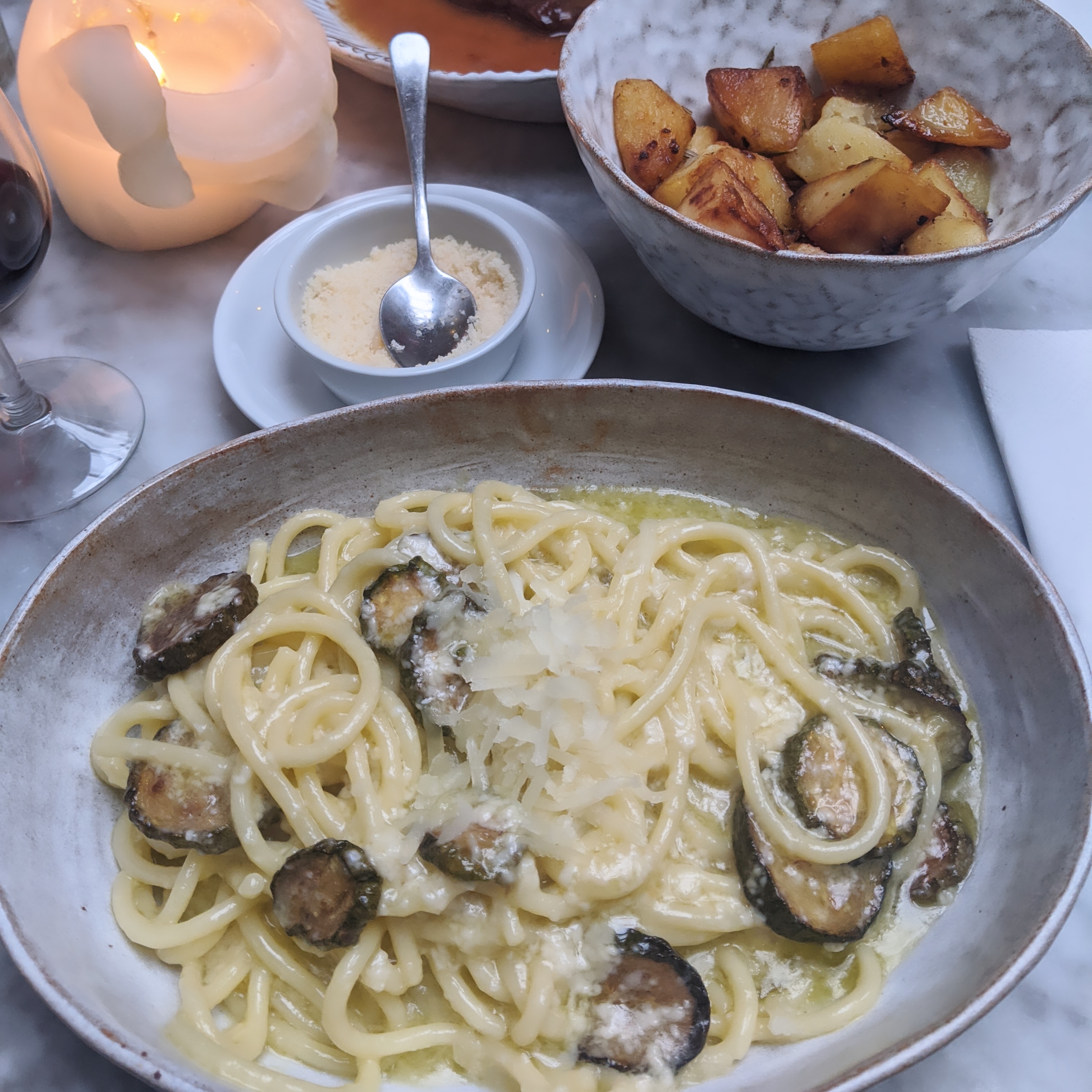 A plate of spaghetti with courgettes next to a bowl of fried potatoes at Campania near Columbia Road