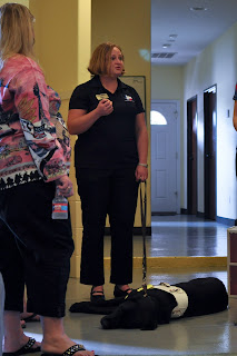 Sandy standing with guide in training at her feet, we are now all crowded into the kennel area.