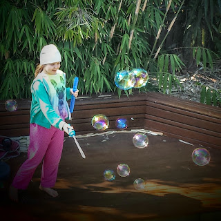 Photo of young girl making giant bubbles in the garden