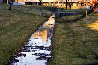 Ditch with water that runs alongside the paved path in Brookbanks Park.