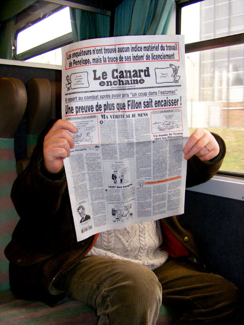 Man reading Le canard enchaine on a train, Loir et Cher, France. Photo by Loire Valley Time Travel.