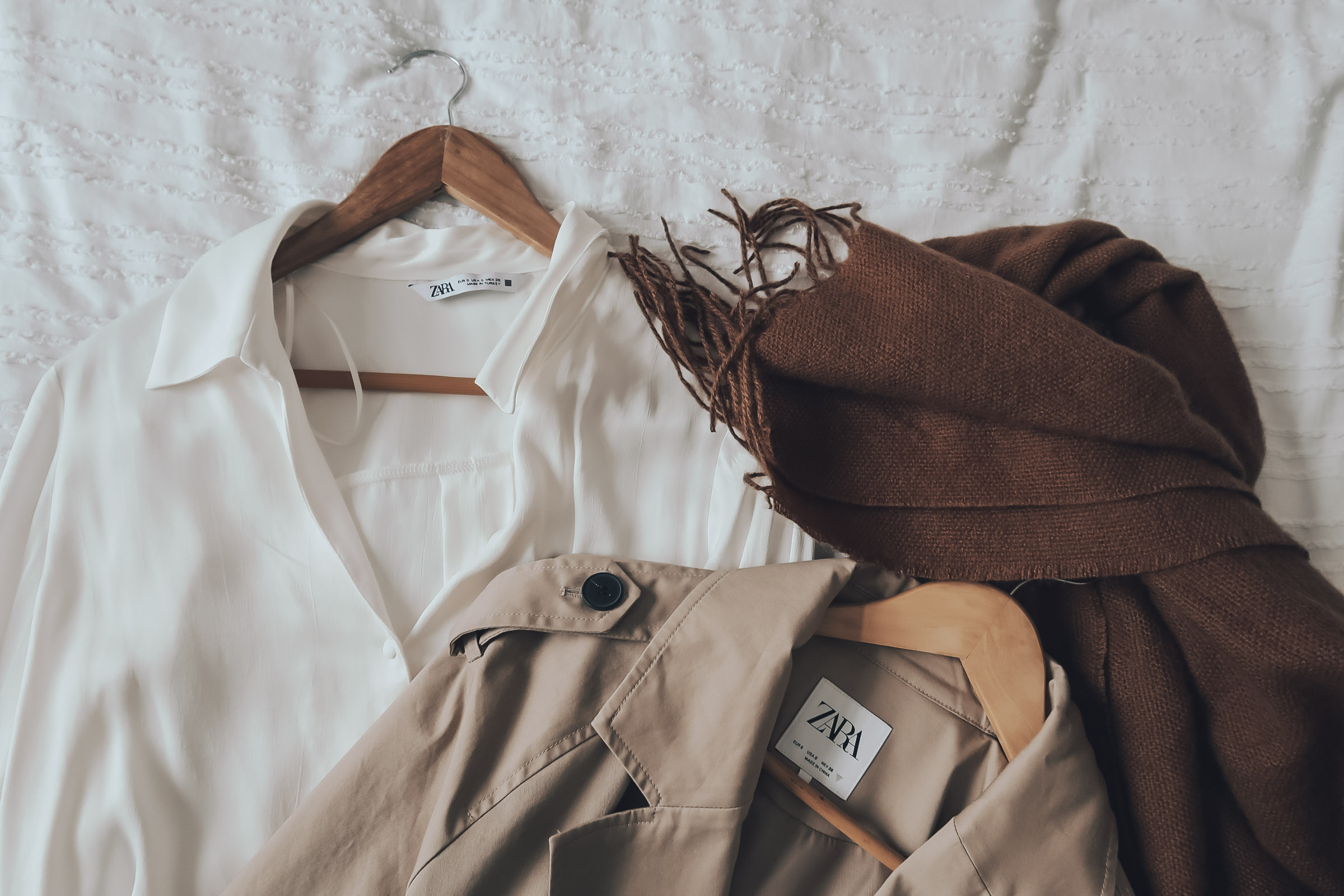 A white blouse, trench coat and brown scarf.