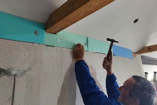 Hammering nails through thin metal to hold the insulation in place