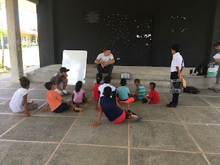 Dr. Dusti showing a video to a dozen kids in the outdoor pavilion.