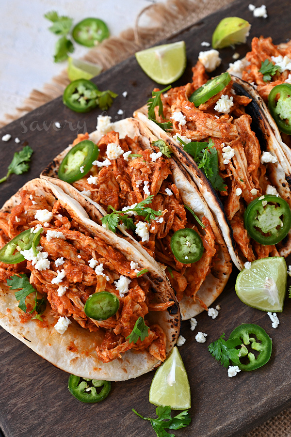 chicken tinga tacos arranged on a wooden serving dish with toppings