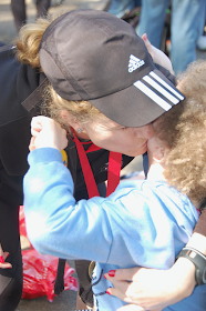 Daisy hugging steph who is wearing a black baseball cap and has a medal around her neck