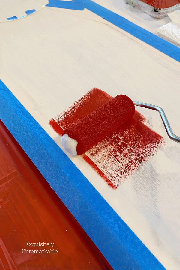 Stencil Roller putting red paint on board