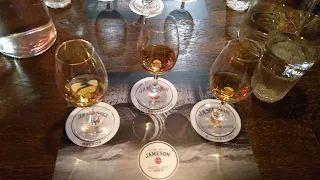 Wood table with 3 medium sized glasses on it. Each glass is partially filled with amber liquid and placed on a coaster that says "Jameson" on it with the Jameson whiskey logo