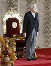 Emperor Akhito of Japan standing in front of his Chrysanthemum throne. You can see the flower emblem on the back of the chair.