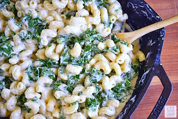 Mac and Cheese with Kale and Bacon mixing in cooked pasta | by Life Tastes Good