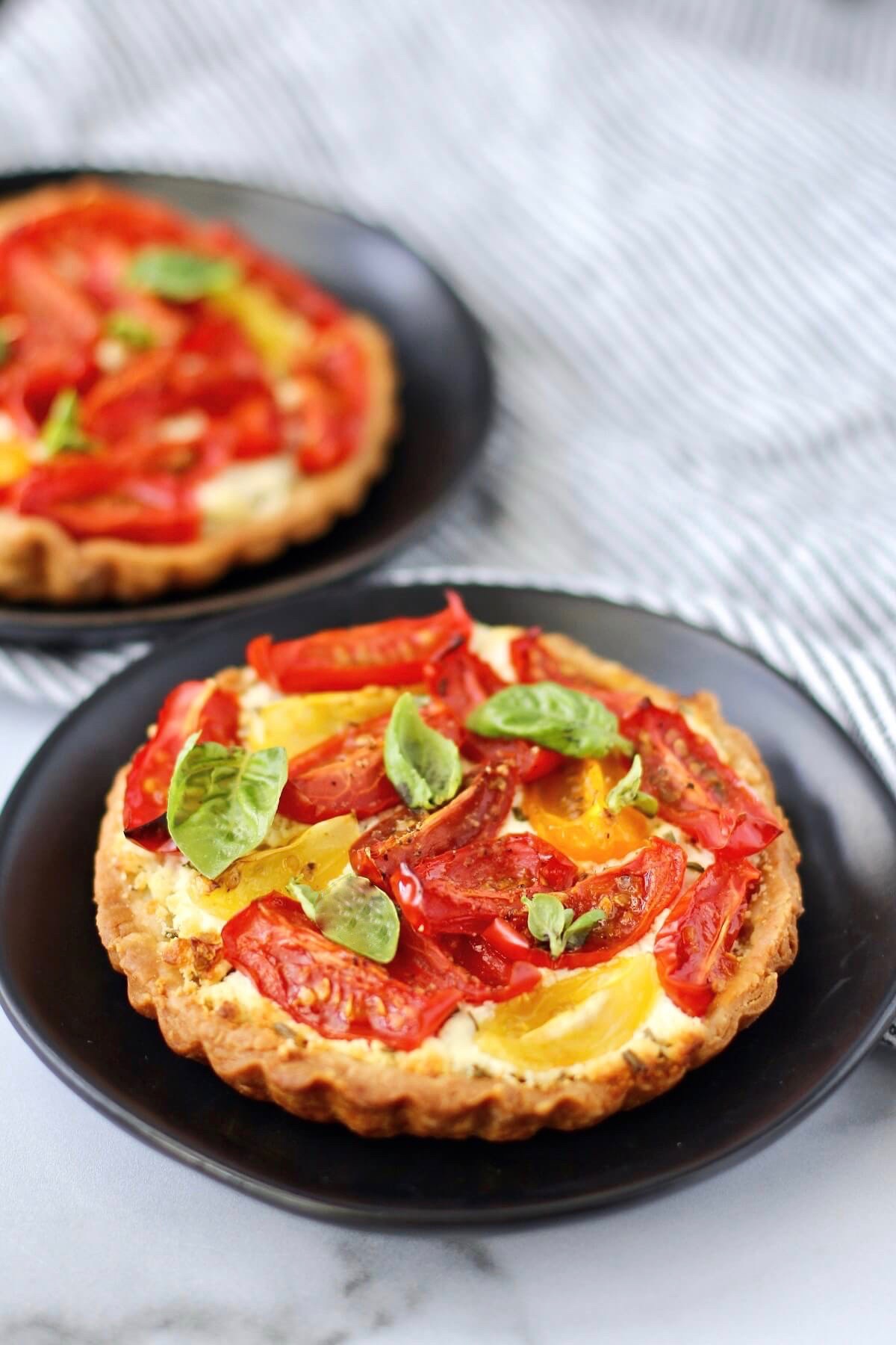 Tomato, basil, and goat cheese tarts on plates.